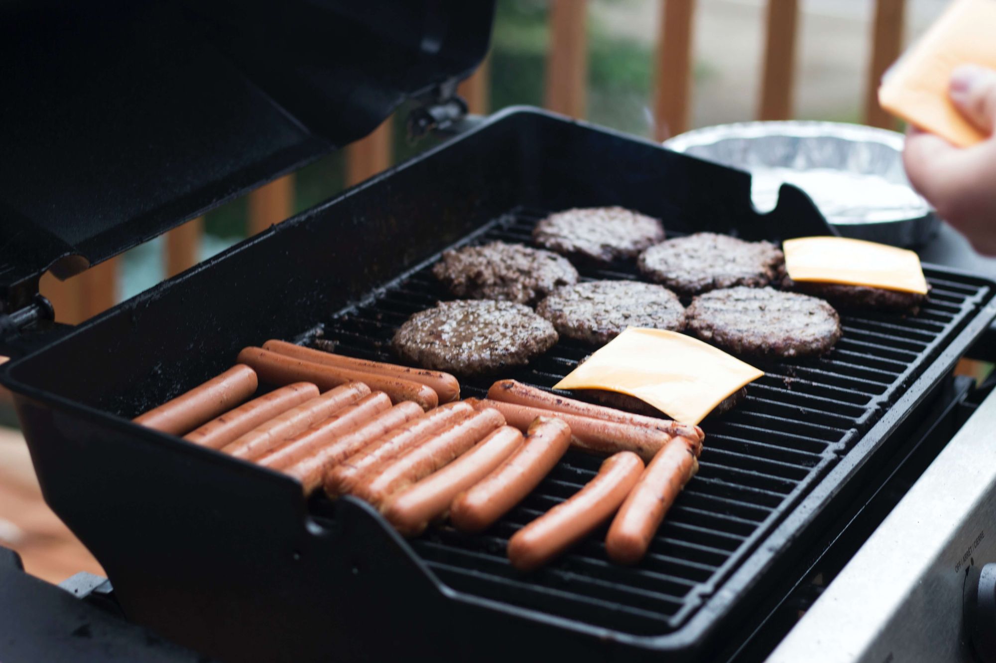 An outdoor grill with burgers and hot dogs cooking.