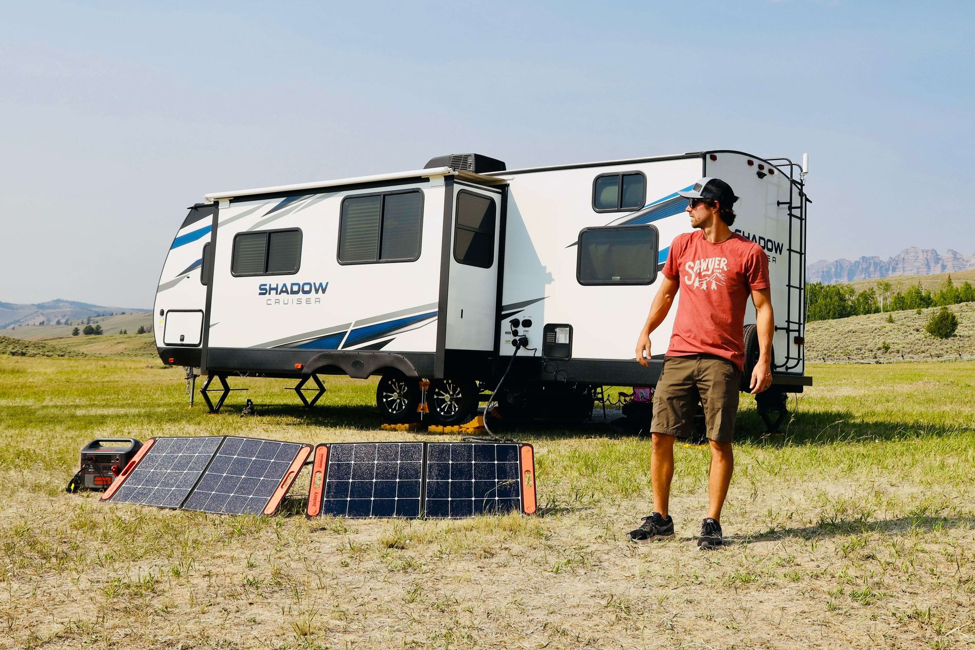 A man and his trailer outside in an open field, with a solar charger and power pack.
